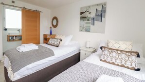 Habitació d'hotel amb dos llits, una porta de fusta, un mirall, una obra d'art a la paret i una nitlínia amb una làmpada.
