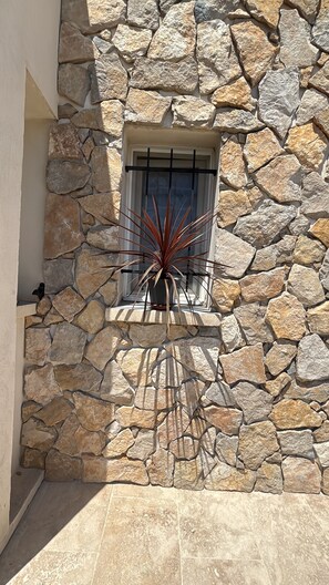 A stone wall with a window and a potted plant. - Calvi Villa jzel F3 bungalow air conditioning swimming pool, pet parking possible 5 km beach (Calvi)