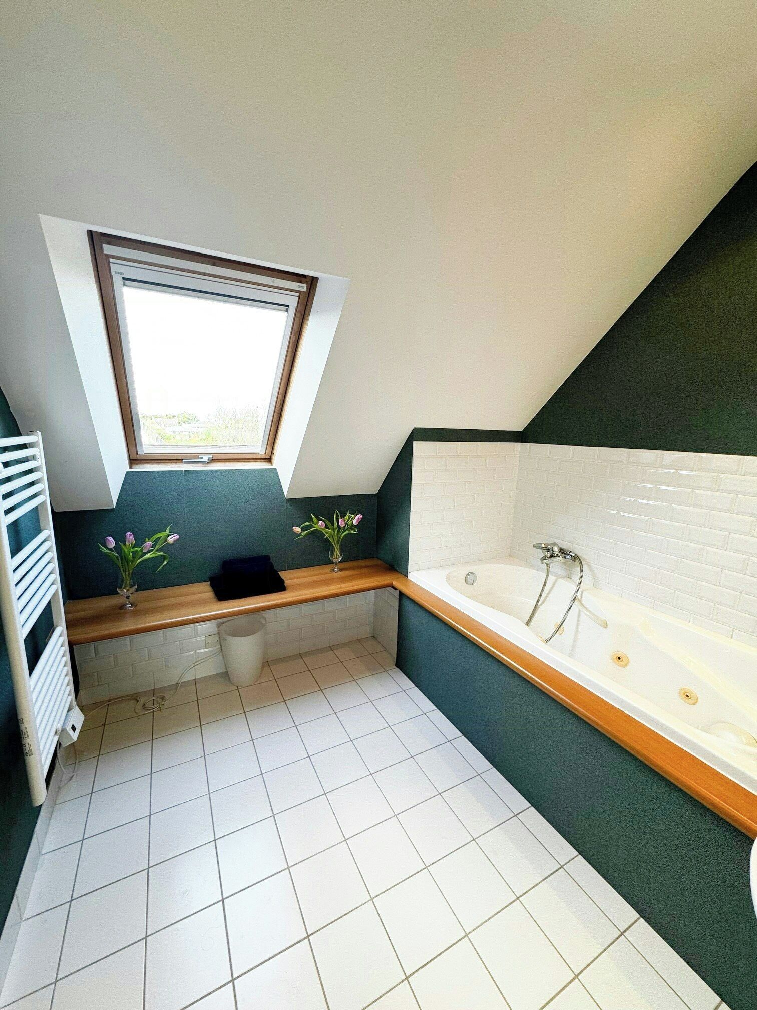 Un baño moderno con tragaluz, bañera, tocador y radiador.