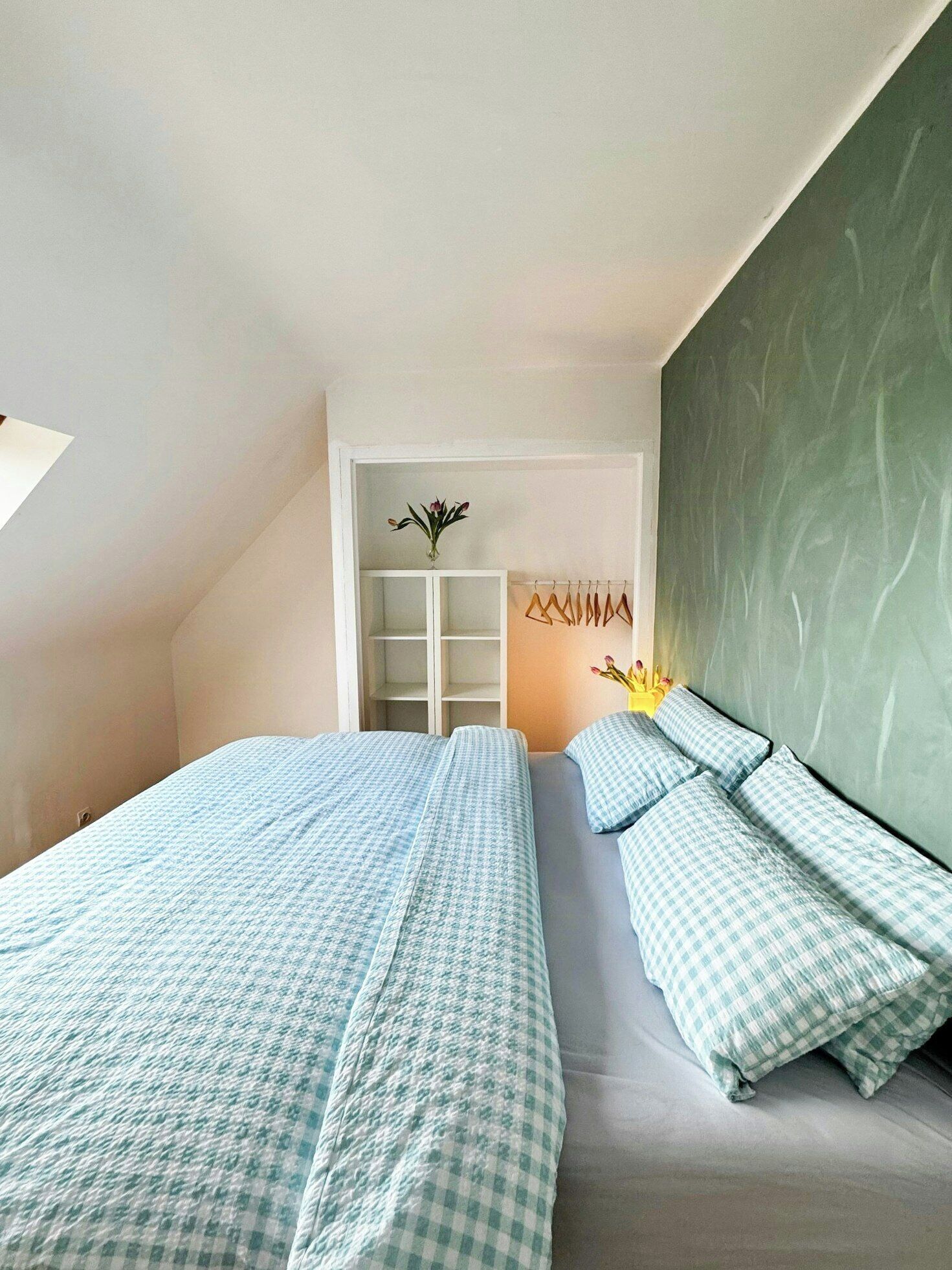 Ein Schlafzimmer mit zwei Betten, einem weißen Kleiderschrank und einer grünen Wand.