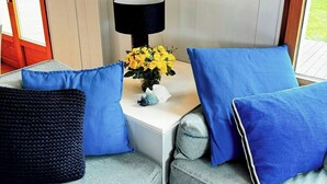 Un coin salon avec un canapé, une lampe et un vase rempli de fleurs jaunes.