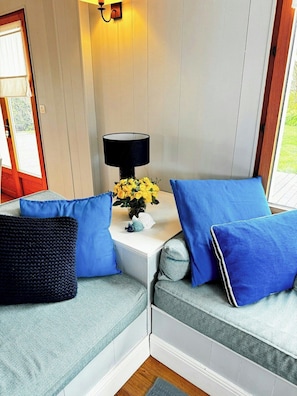 Eine Sitzecke mit einer Couch, einer Lampe und einem Blumenstrauß mit gelben Blumen.