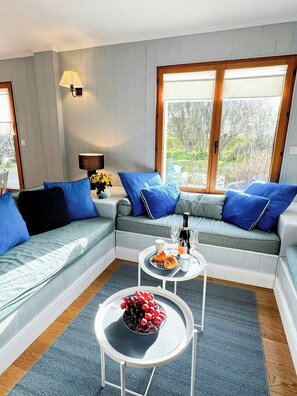 Ein modernes Wohnzimmer mit einer Couch, einem Couchtisch und einem Fenster mit Blick auf Grünflächen.