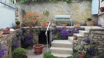 A courtyard with stone steps, potted plants, and a metal bench.