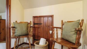 A room with two wooden chairs with cushions, a wooden door, and a woven basket on the floor.