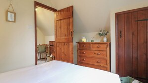 Un dormitorio con cama, cómoda de madera y un contenedor verde para guardar cosas.