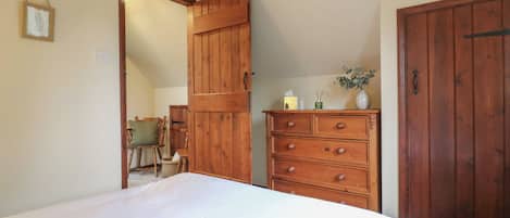 A bedroom with a bed, wooden dresser, and a green storage bin.
