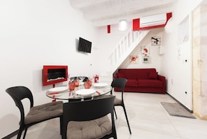 Ein moderner Wohnraum mit Essbereich, einem roten Sofa und einer Treppe, die in eine obere Ebene führt.