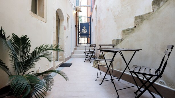 An indoor corridor with a narrow walkway, a bench, and a table. - LE CORTI - Fuoco by OrtigiaApartments (Syracuse)