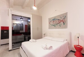 Ein Hotelzimmer mit einem Bett, einer roten Lampe, einem Bild von einem Fisch und einem Kleiderschrank.