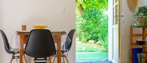 A dining area with a table, chairs, and a view of a garden through an open door.