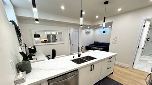 Una cocina moderna con lavavajillas integrado, un lavamanos doble e iluminación colgante.