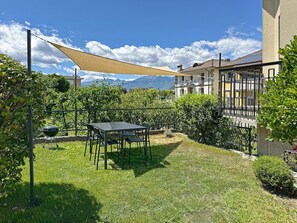 Une terrasse avec une table et des chaises, entourée de verdure et offrant une vue sur les montagnes.