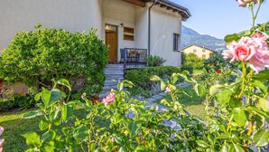 Une maison avec un jardin, une porte en bois et une montagne en arrière-plan.