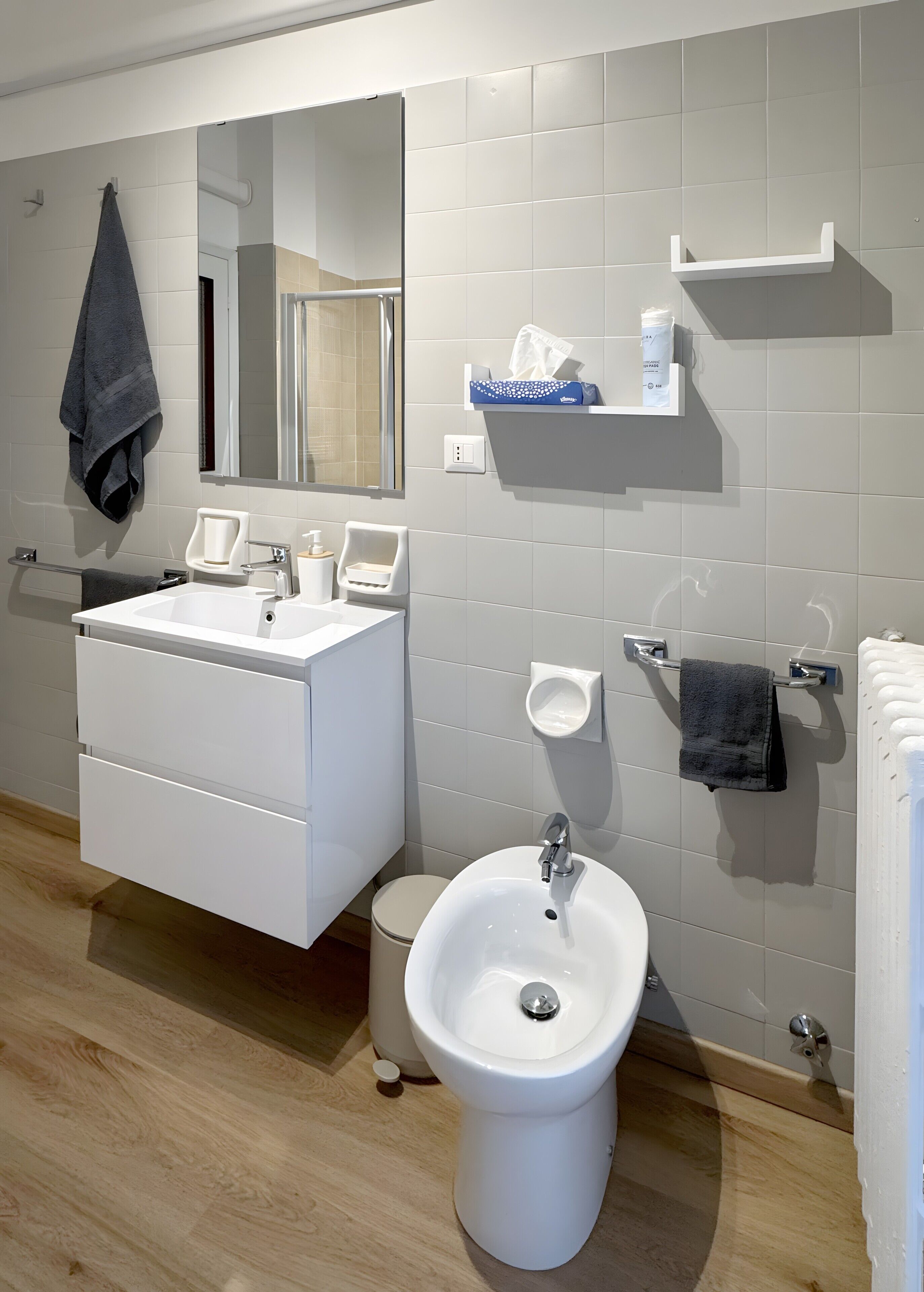 Un bagno moderno con lavandino, bidet e mobile contenitore bianchi.