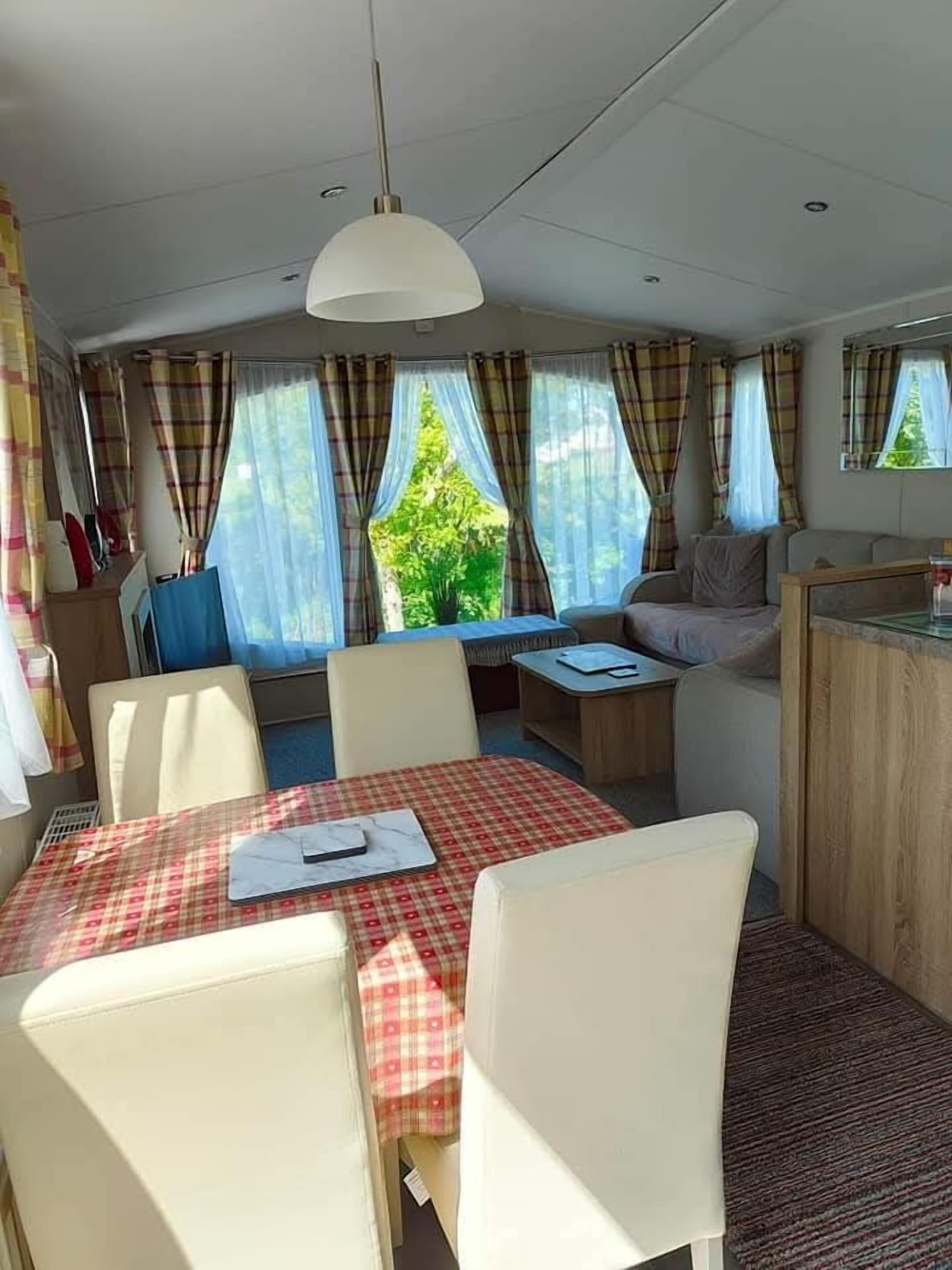 Un espacio habitable compacto con una mesa de comedor, sillas, un sofá y una pequeña cocina.