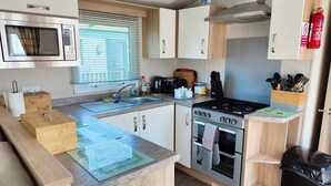 Eine kompakte Küche mit Mikrowelle, Herd, Backofen, Spüle und Holzausstattung.