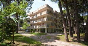 Ein mehrgeschossiges Wohnhaus mit Balkonen, umgeben von Bäumen und einem Kiesweg.