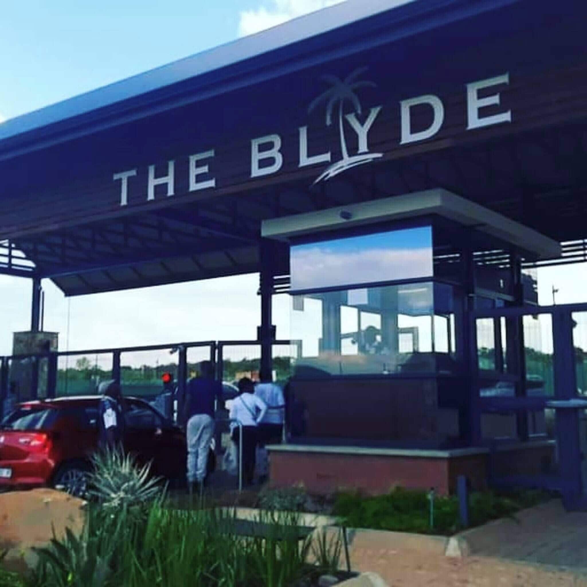 A hotel entrance with a sign reading 'THE BLYDE' and a glass enclosure.