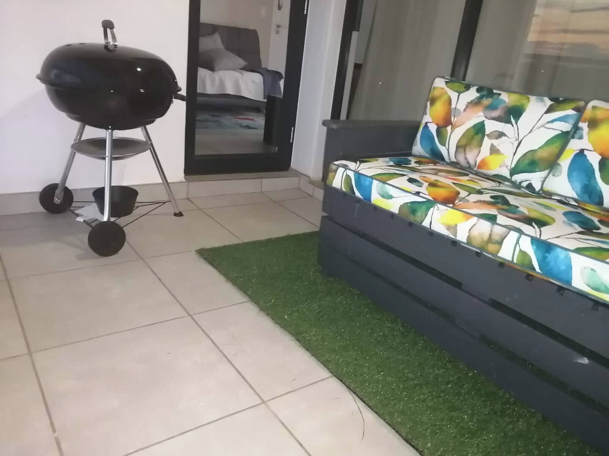 A room with a sofa, a grill, and a door leading to another room.