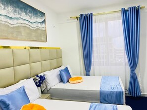 Une chambre d’hôtel avec un lit, une tête de lit, une fenêtre avec des rideaux et un tableau au mur.