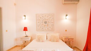 A hotel room with a bed, two bedside tables, a red lamp, a wall tapestry, and towels on the floor. - Villa with heatable pool and BBQ in Carvoeiro (Carvoeiro)
