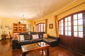 A living room with a leather sofa, a glass coffee table, a wooden cabinet, and a dining area with a table and chairs. - Villa with heatable pool and BBQ in Carvoeiro (Carvoeiro)