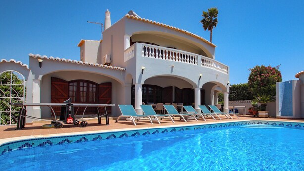 A poolside area with lounge chairs, a table, and a covered seating area. - Villa with heatable pool and BBQ in Carvoeiro (Carvoeiro)