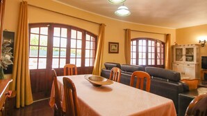 A dining area with a table, chairs, and a large window with curtains. - Villa with heatable pool and BBQ in Carvoeiro (Carvoeiro)
