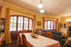 A dining area with a table, chairs, and a large window with curtains. - Villa with heatable pool and BBQ in Carvoeiro (Carvoeiro)