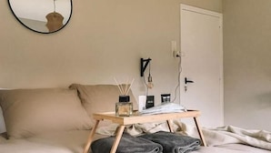 Quarto com cama, mesa de cabeceira, espelho e porta.