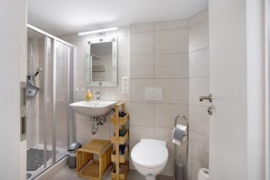 Ein Badezimmer mit Dusche, Waschbecken, Toilette und einem Holzschrank.