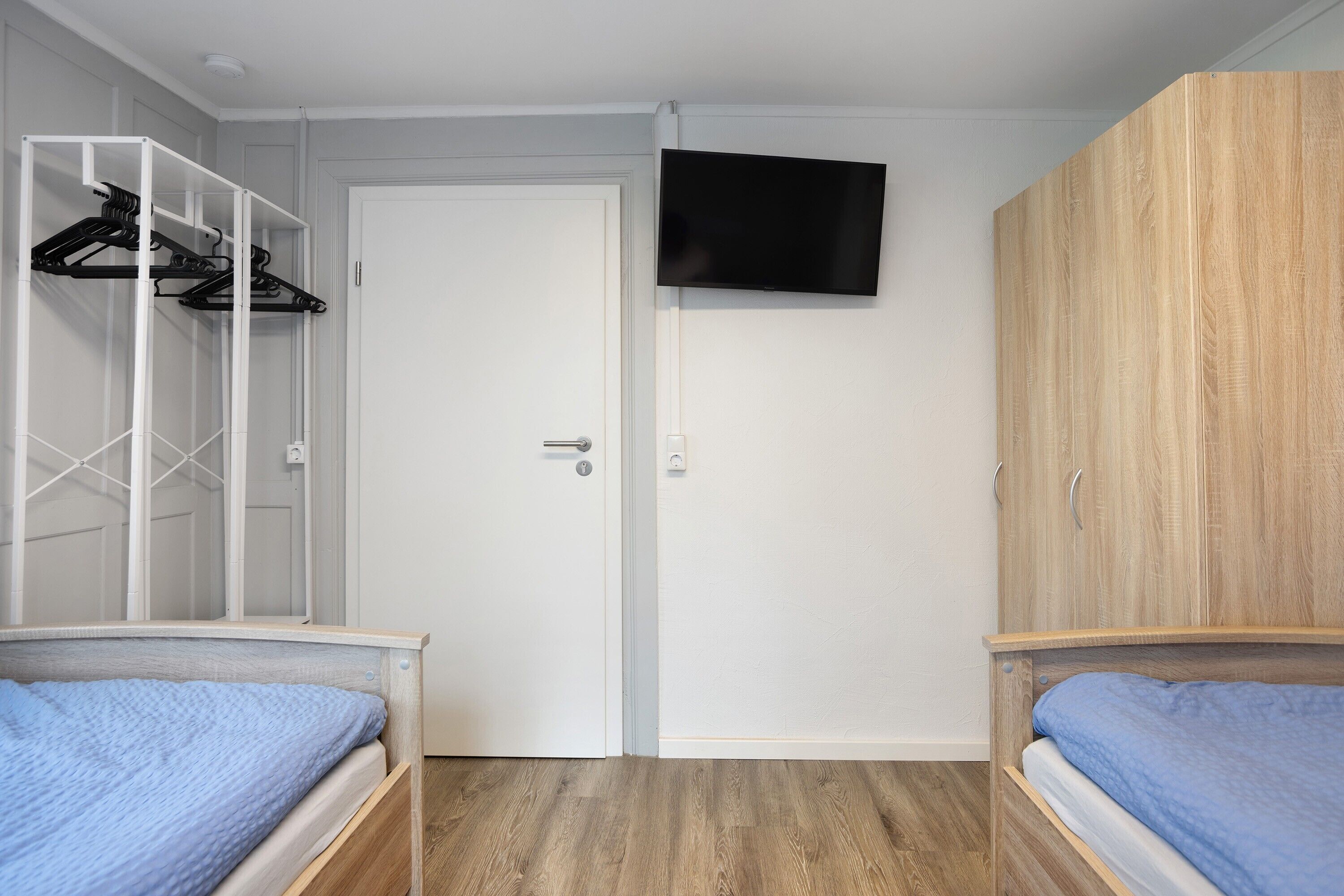Une chambre avec deux lits, une télévision, une armoire et un placard avec une tringle pour suspendre les vêtements.