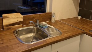 A kitchen with a stainless steel sink, wooden countertop, and white cabinets.