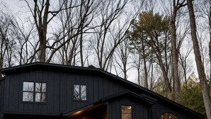 A two-story cabin with a balcony, wooden deck, and a large arched window. - Luxurious Smoky Mountain Getaway Hot Tub 💦 Pool Sauna & Fishing 🐠 EV Charge ⚡️ (Sevierville)