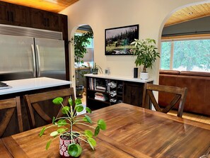 Eine Küche mit Holztisch, Stühlen, einem Kühlschrank und einem Essbereich mit Blick ins Freie.