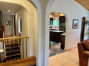 Ein modernes Interieur mit Treppe, Holzboden und einer Küchenzeile mit dunklen Schränken und einem Fenster.