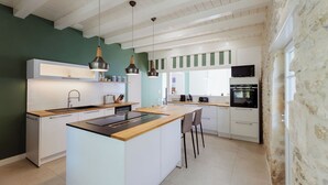 Een moderne keuken met een centraal eiland, witte kasten en hanglampen.