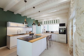 Een moderne keuken met een centraal eiland, witte kasten en hanglampen.