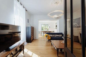Een moderne woonkamer met een televisie, bank en eethoek.