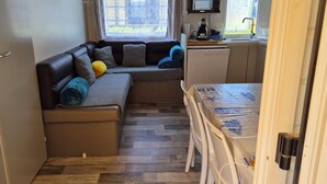 Een knus woongedeelte met een bank, een kitchenette en een eettafel.