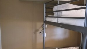 Een stapelbed met een houten hoofdbord, een metalen ladder en een witte matras.