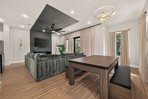 A modern living room with a sectional sofa, a dining table, and a flat-screen TV. - Sleep In Style Fashion House W/Pool Table Sleep 10 (Houston)