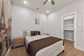 A bedroom with a bed, bedside tables, a wardrobe, a ceiling fan, recessed lighting, and a wall-mounted artwork. - Sleep In Style Fashion House W/Pool Table Sleep 10 (Houston)