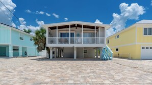 A beachfront property with a covered patio, a staircase, and a garage. - 🌊 Palermo Paradise | 3BR Fort Myers Beach | Heated Pool + Porch Swing (Fort Myers Beach)