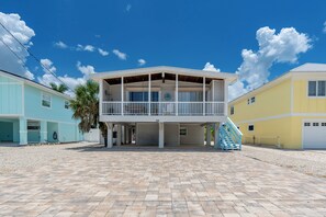 Ein Strandgrundstück mit überdachter Terrasse, einer Treppe und einer Garage.