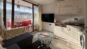 Un apartamento moderno con balcón, comedor, cocina equipada con lavadora y televisor.