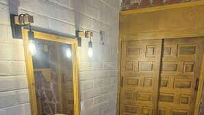 Un baño con tocador de madera, un espejo grande, dos puertas y piso de baldosas.