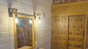 Ein Badezimmer mit einem Holzkosmetikschrank, einem beleuchteten Spiegel, einem Handtuchhalter und einer Doppeltür.