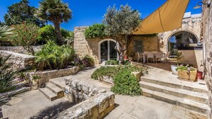 Un patio con escalones de piedra, una mesa y sillas, y un árbol grande.